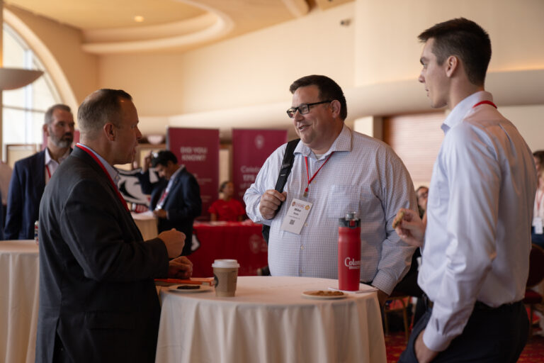 three men talking to each other around a table