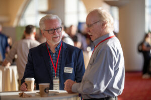 two men talking to each other in a crowded room